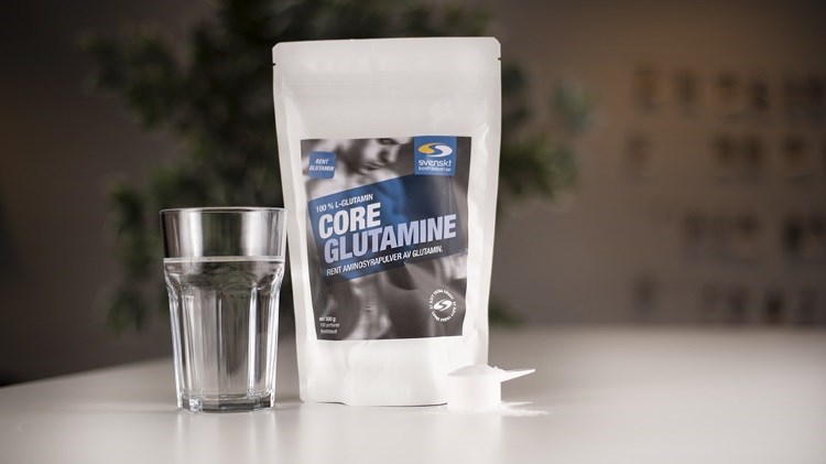 En pse Core Glutamine p bord med ett glas vatten. 